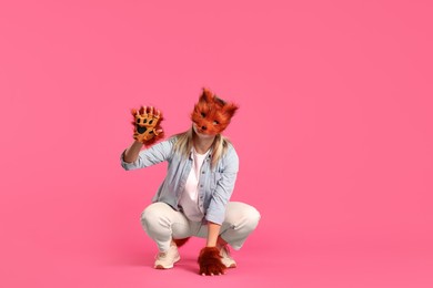 Photo of Quadrobics. Woman wearing fox mask and gloves pink background