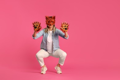 Photo of Quadrobics. Woman wearing fox mask and gloves pink background