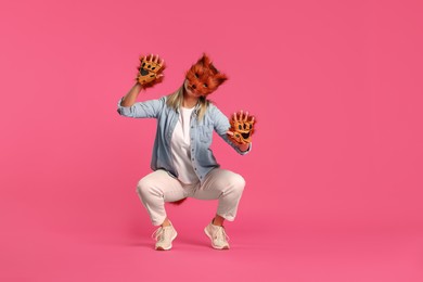 Photo of Quadrobics. Woman wearing fox mask and gloves pink background