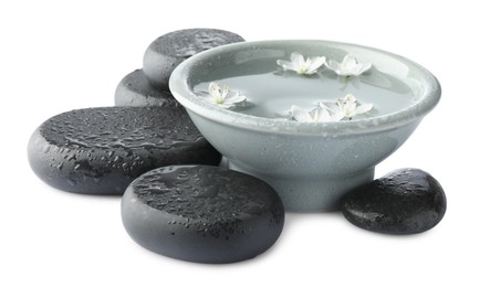 Photo of Wet spa stones and bowl of water with beautiful flowers isolated on white