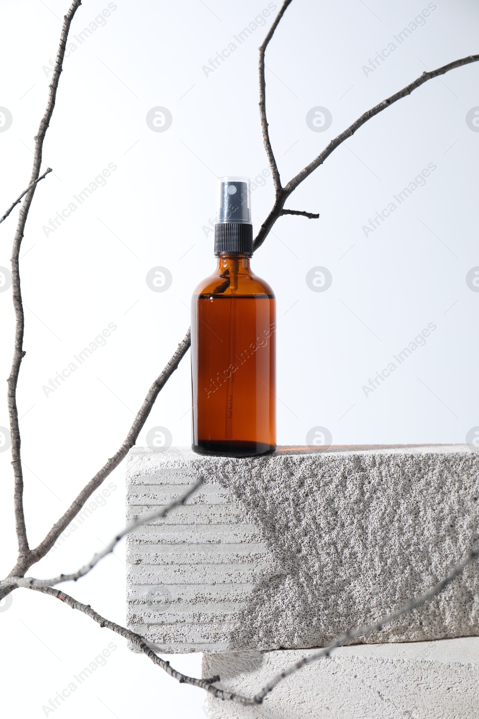 Photo of Bottle of cosmetic product on concrete block and tree branch against white background