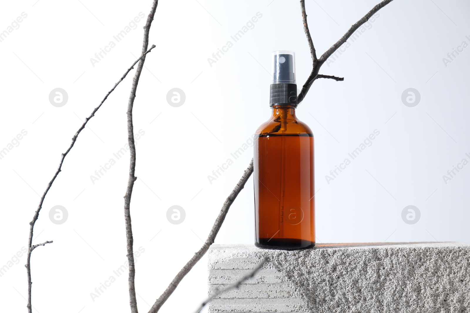 Photo of Bottle of cosmetic product on concrete block and tree branch against white background