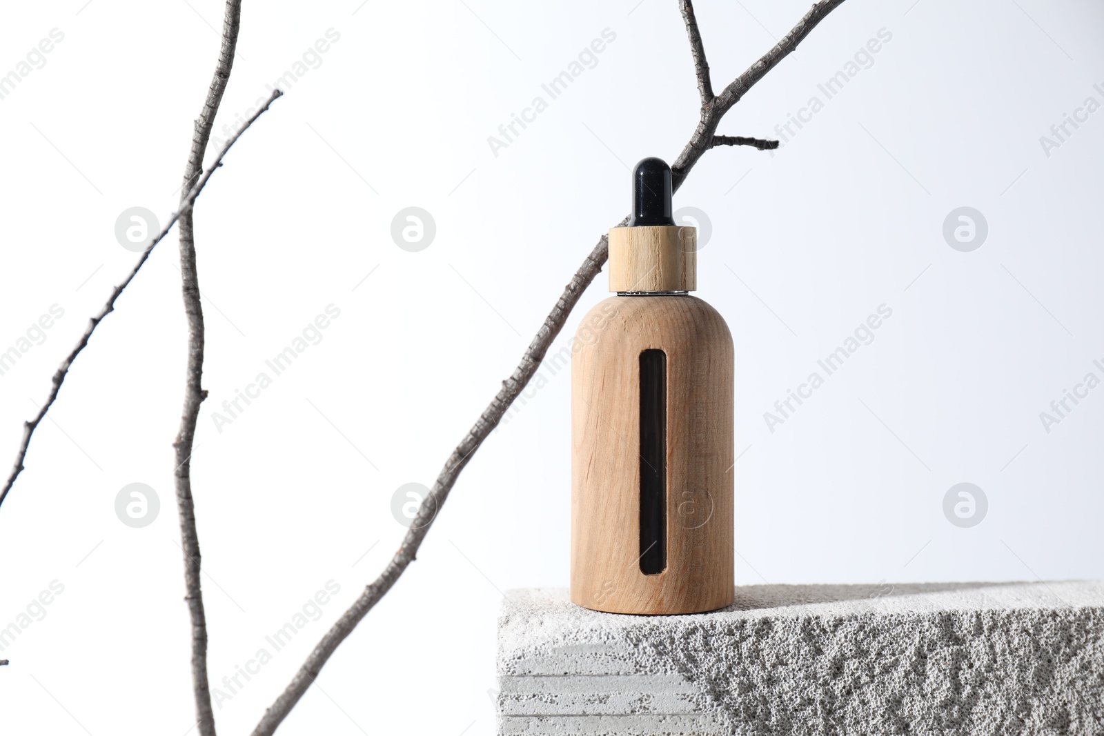 Photo of Bottle of cosmetic product on concrete block and tree branch against white background