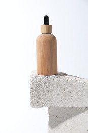 Bottle of cosmetic product on concrete block against white background