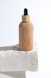 Bottle of cosmetic product on concrete block against white background