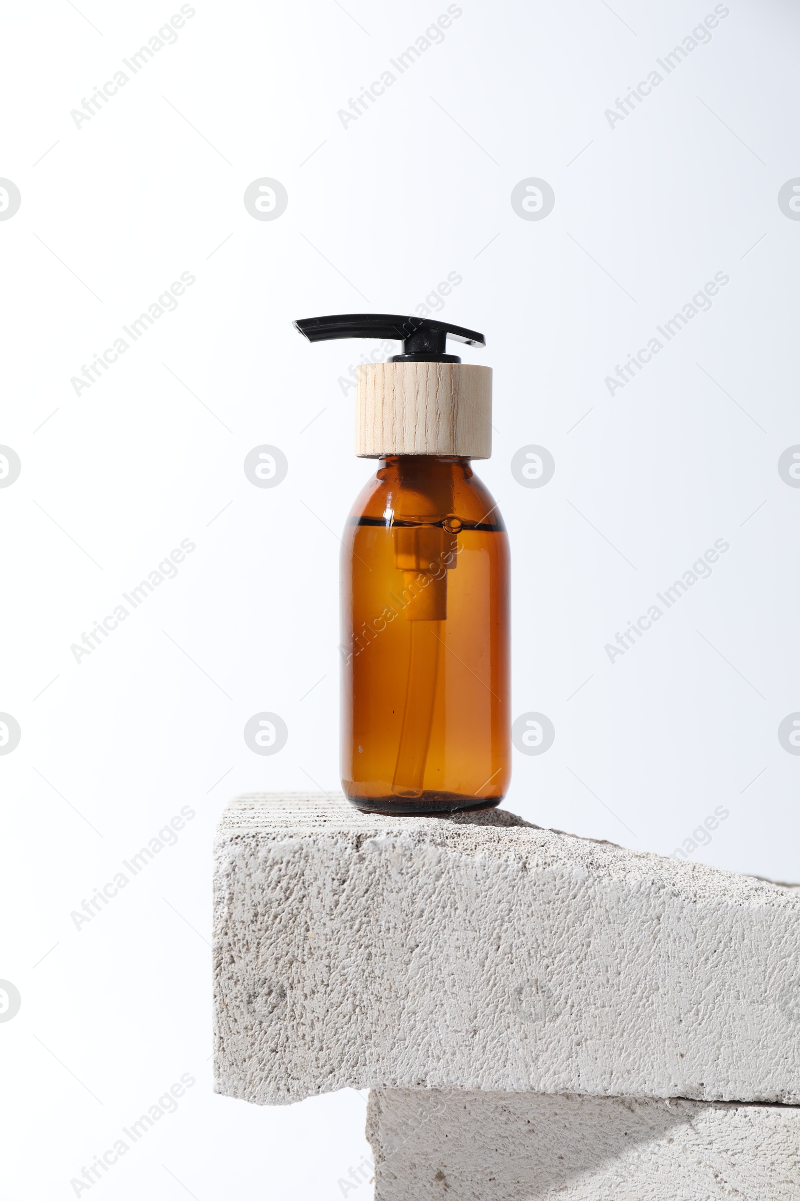 Photo of Bottle of cosmetic product on concrete block against white background