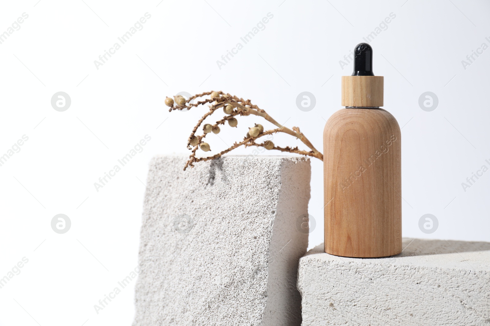 Photo of Bottle of cosmetic product and mullein plant on concrete blocks against white background, space for text