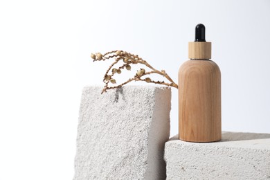 Photo of Bottle of cosmetic product and mullein plant on concrete blocks against white background, space for text