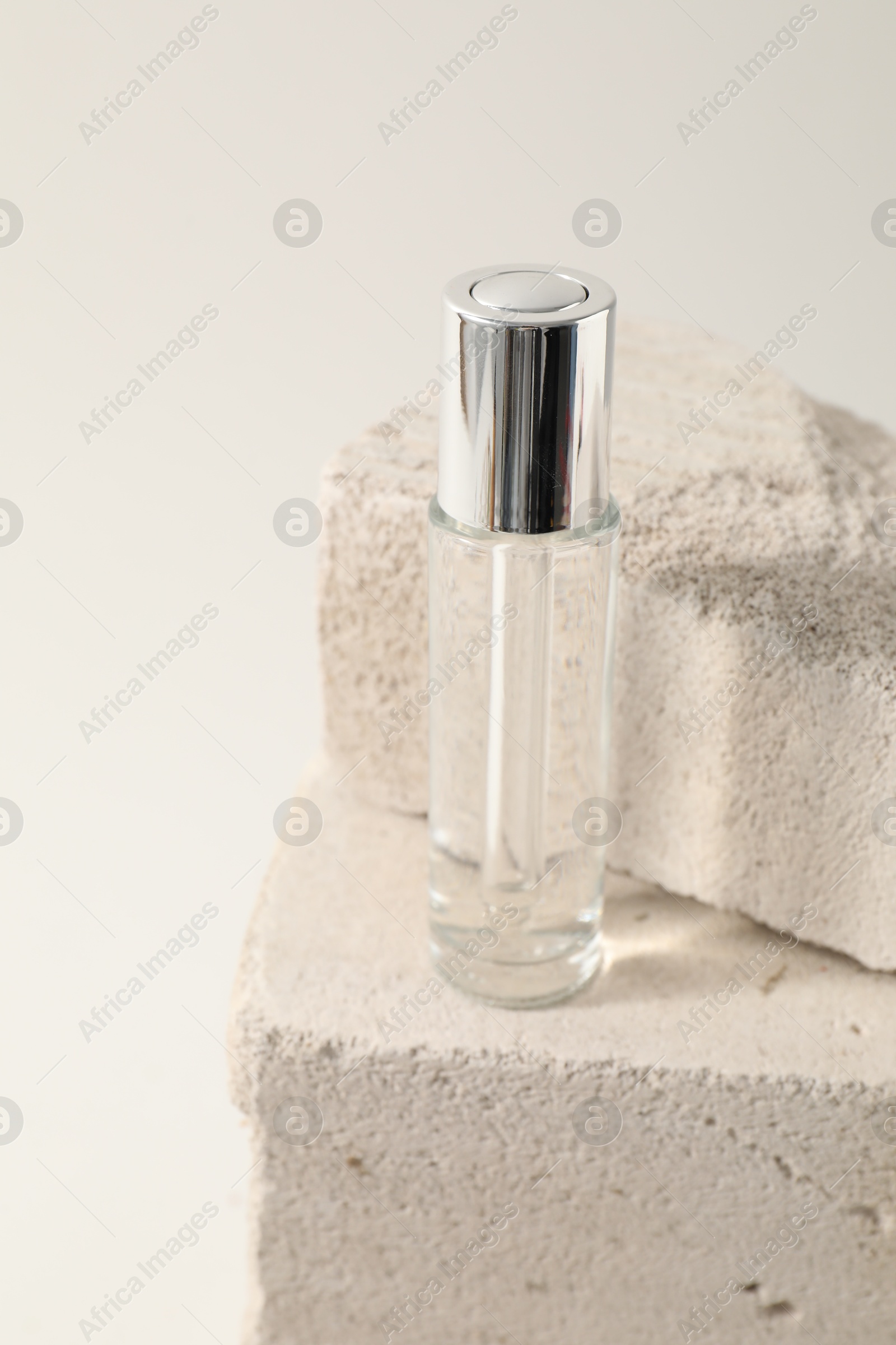 Photo of Bottle of serum on concrete block against white background