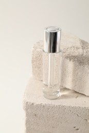 Bottle of serum on concrete block against white background