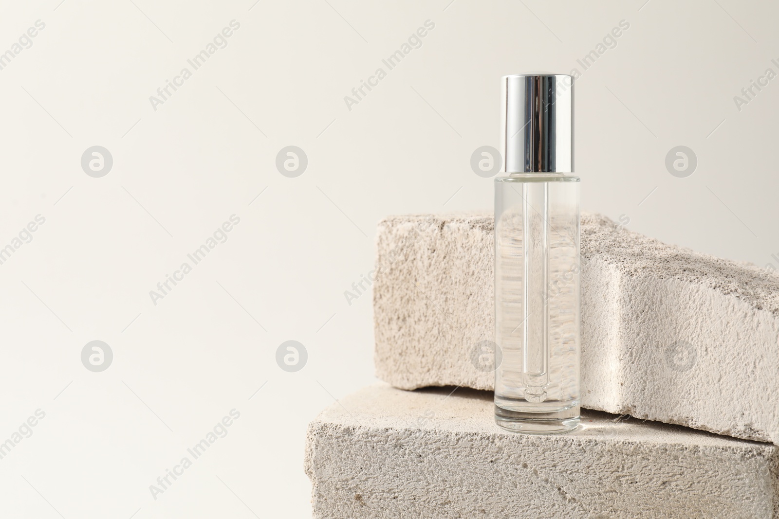 Photo of Bottle of serum on concrete block against white background, space for text