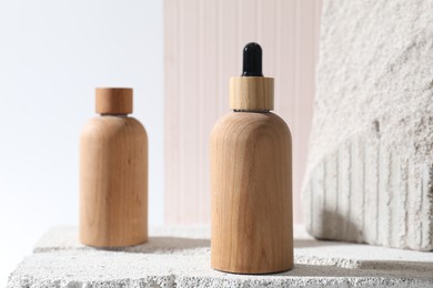 Bottles of cosmetic products on concrete block against light background