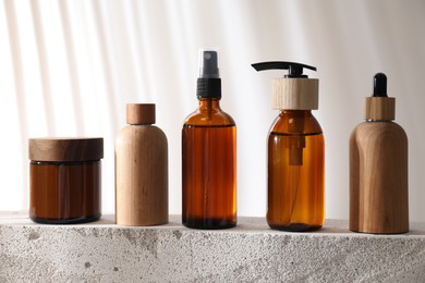 Different cosmetic products on concrete surface against light background