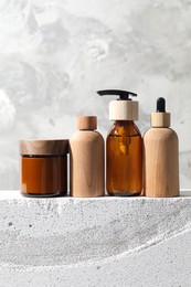 Different cosmetic products on concrete surface against gray background