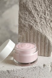 Photo of Jar of cream and lid on concrete block