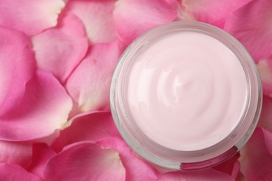 Photo of Jar of cream on pink petals, top view