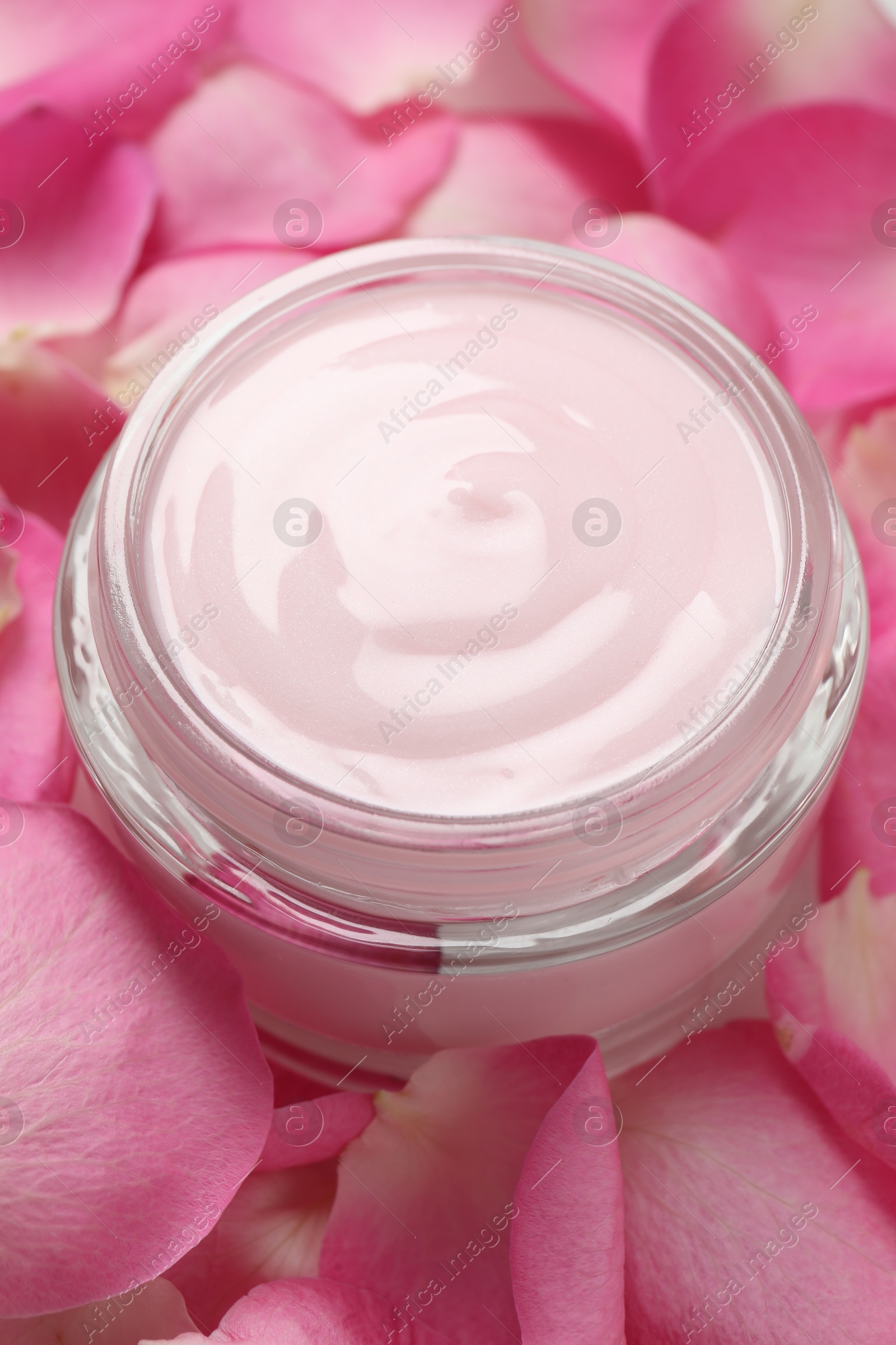 Photo of Jar of cream on pink petals, closeup