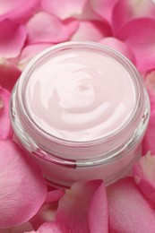 Photo of Jar of cream on pink petals, closeup