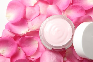 Jar of cream on pink petals, top view