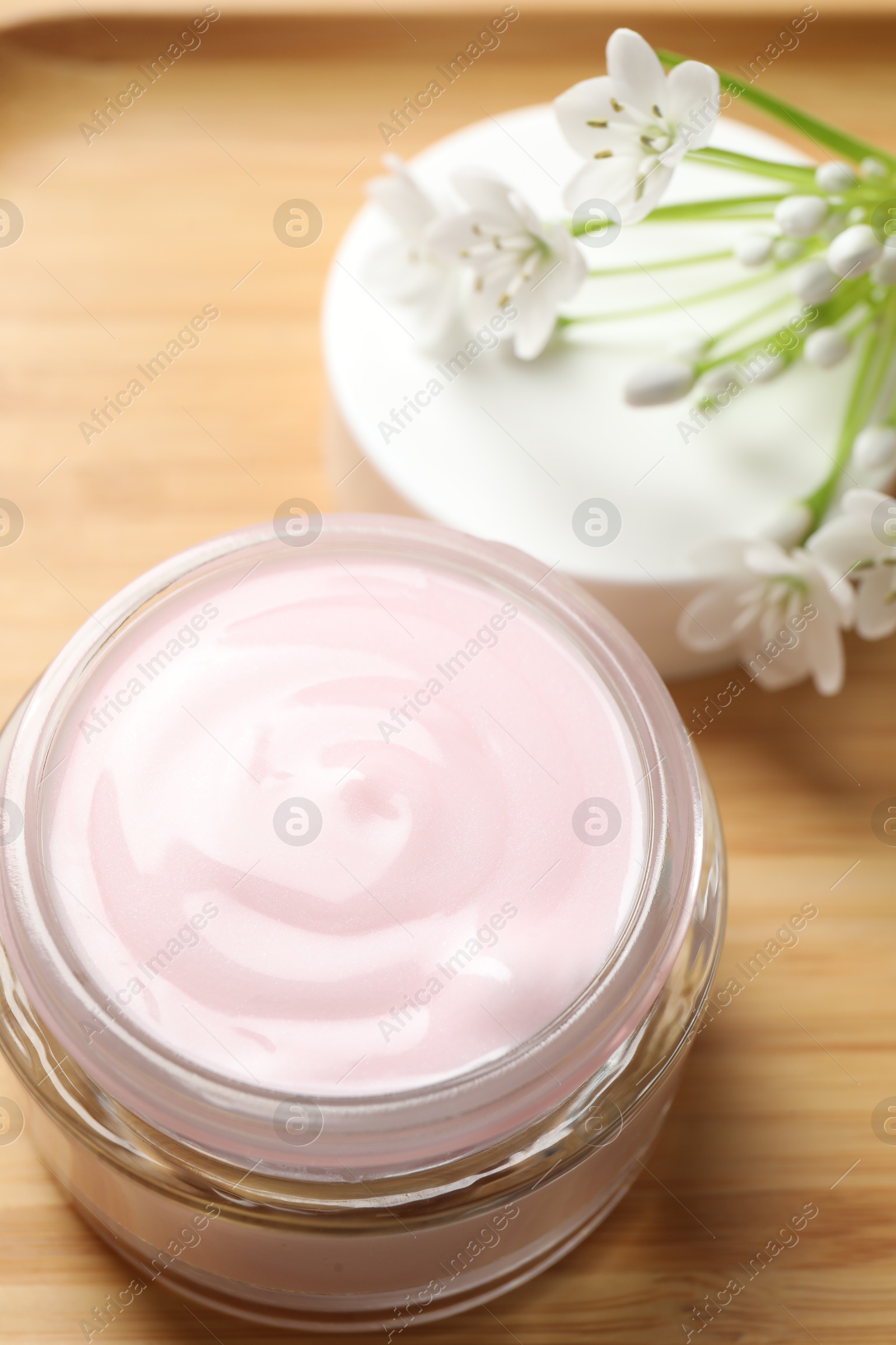 Photo of Jar of cream and beautiful white flowers on table, closeup