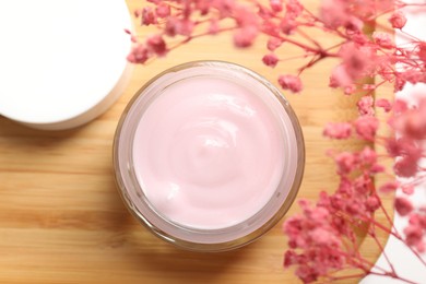 Photo of Jar of cream and pink gypsophila flowers on table, top view