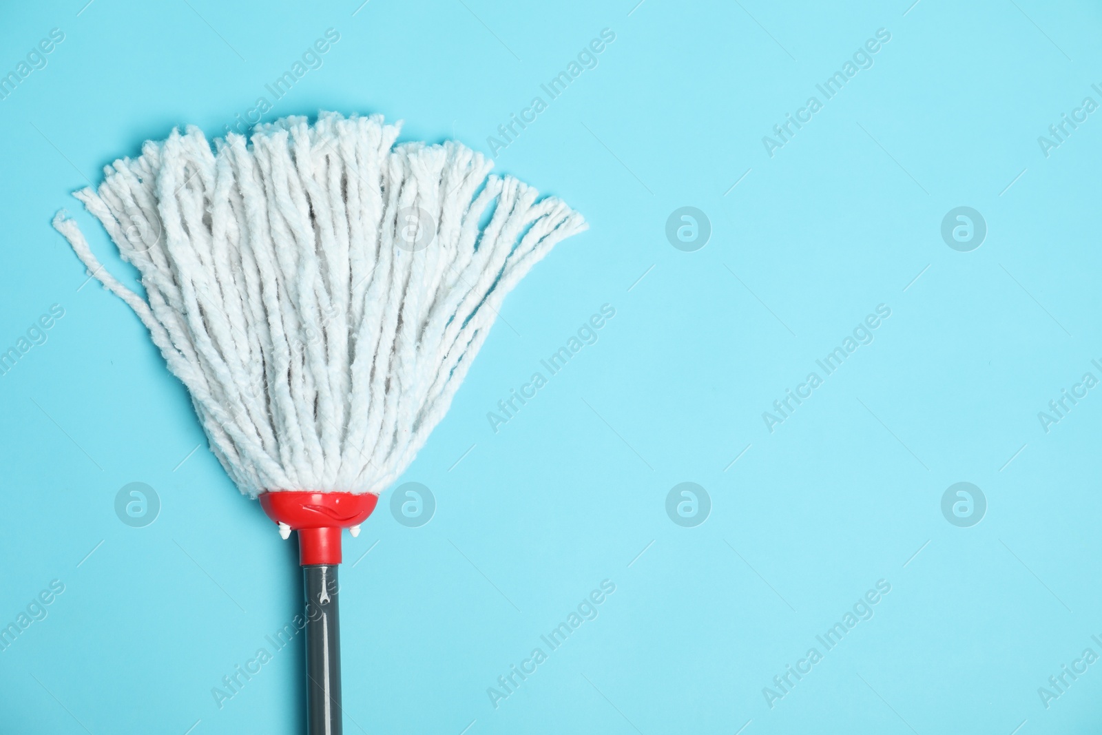 Photo of String mop on light blue background, top view. Space for text