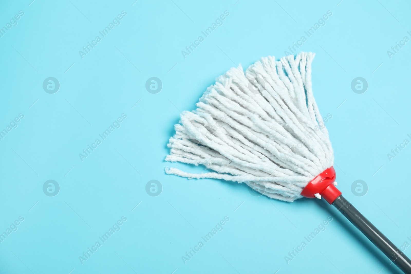 Photo of String mop on light blue background, above view. Space for text