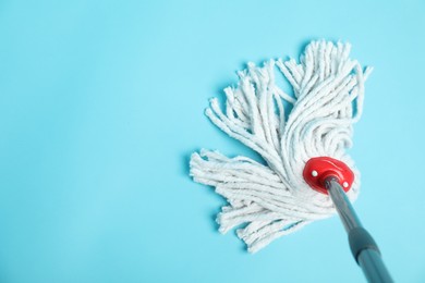 Photo of String mop on light blue background, top view. Space for text