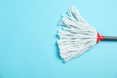 Photo of String mop on light blue background, top view. Space for text