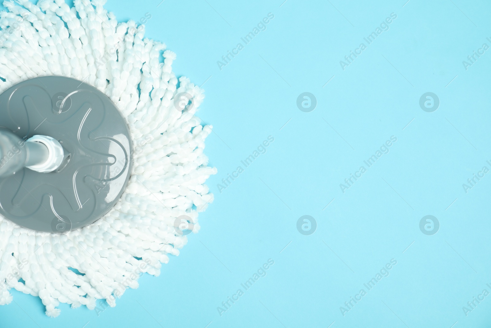 Photo of String mop on light blue background, top view. Space for text