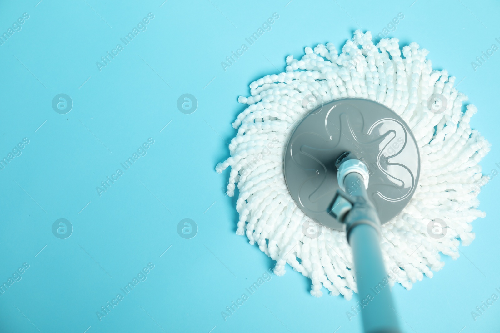 Photo of String mop on light blue background, top view. Space for text