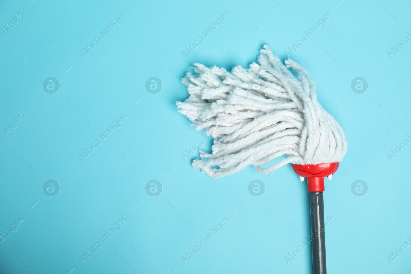 Photo of String mop on light blue background, top view. Space for text