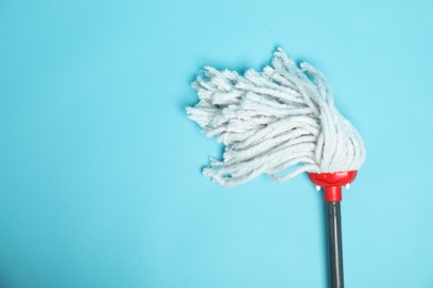 Photo of String mop on light blue background, top view. Space for text