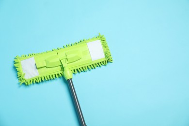 Microfiber mop on light blue background, top view. Space for text