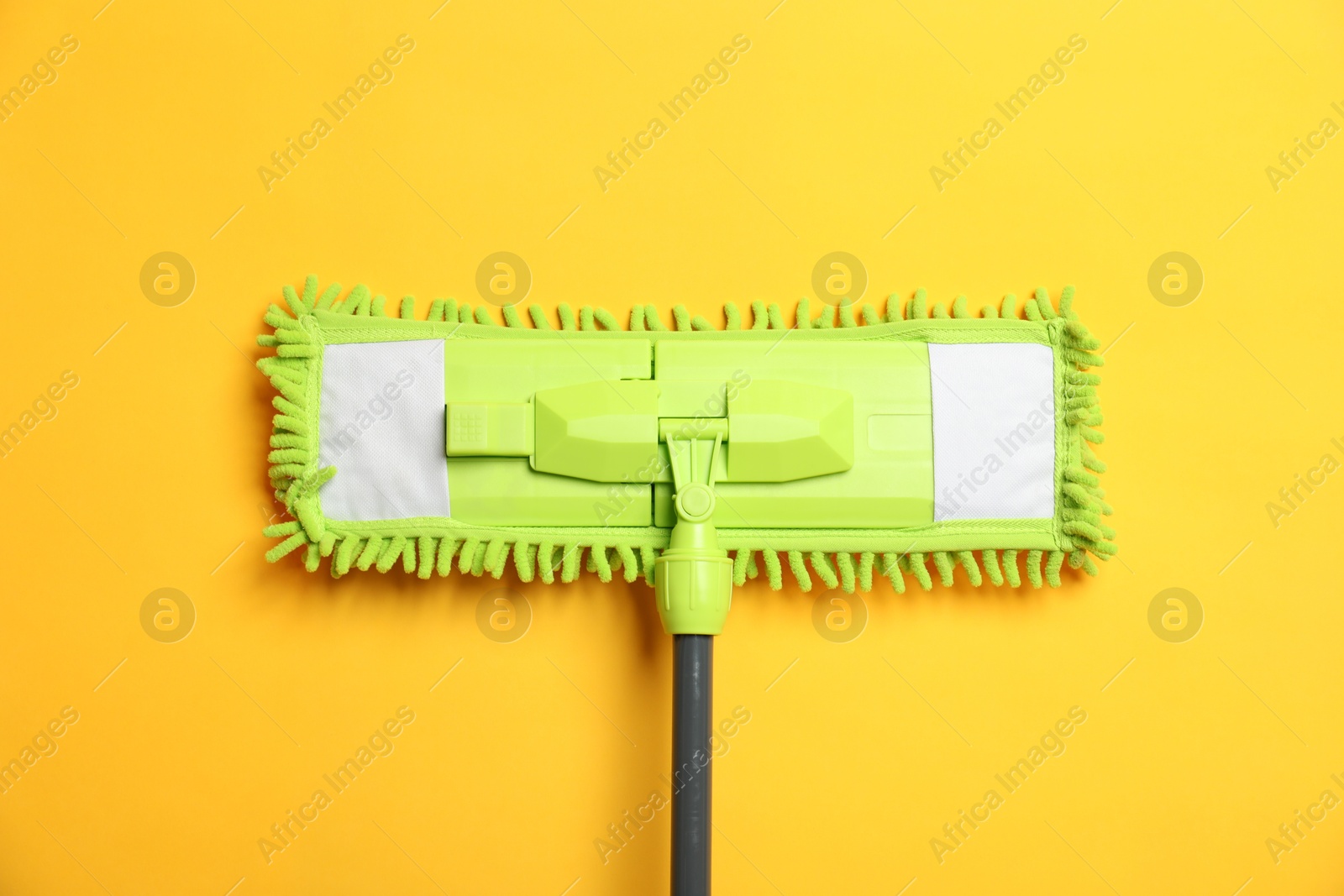 Photo of Microfiber mop on yellow background, top view. Cleaning equipment