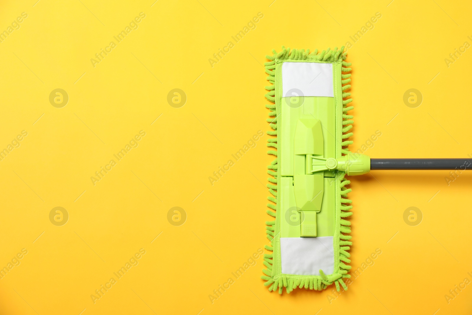 Photo of Microfiber mop on yellow background, top view. Space for text