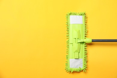 Microfiber mop on yellow background, top view. Space for text