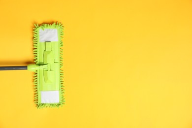 Photo of Microfiber mop on yellow background, top view. Space for text