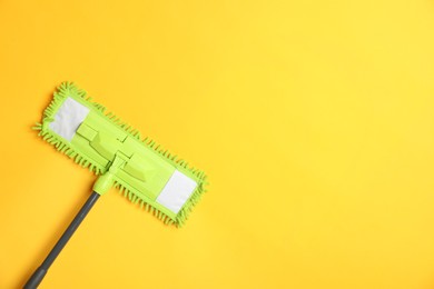 Microfiber mop on yellow background, top view. Space for text