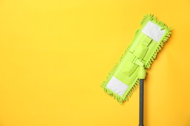 Photo of Microfiber mop on yellow background, top view. Space for text