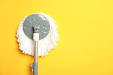 String mop on yellow background, top view. Space for text