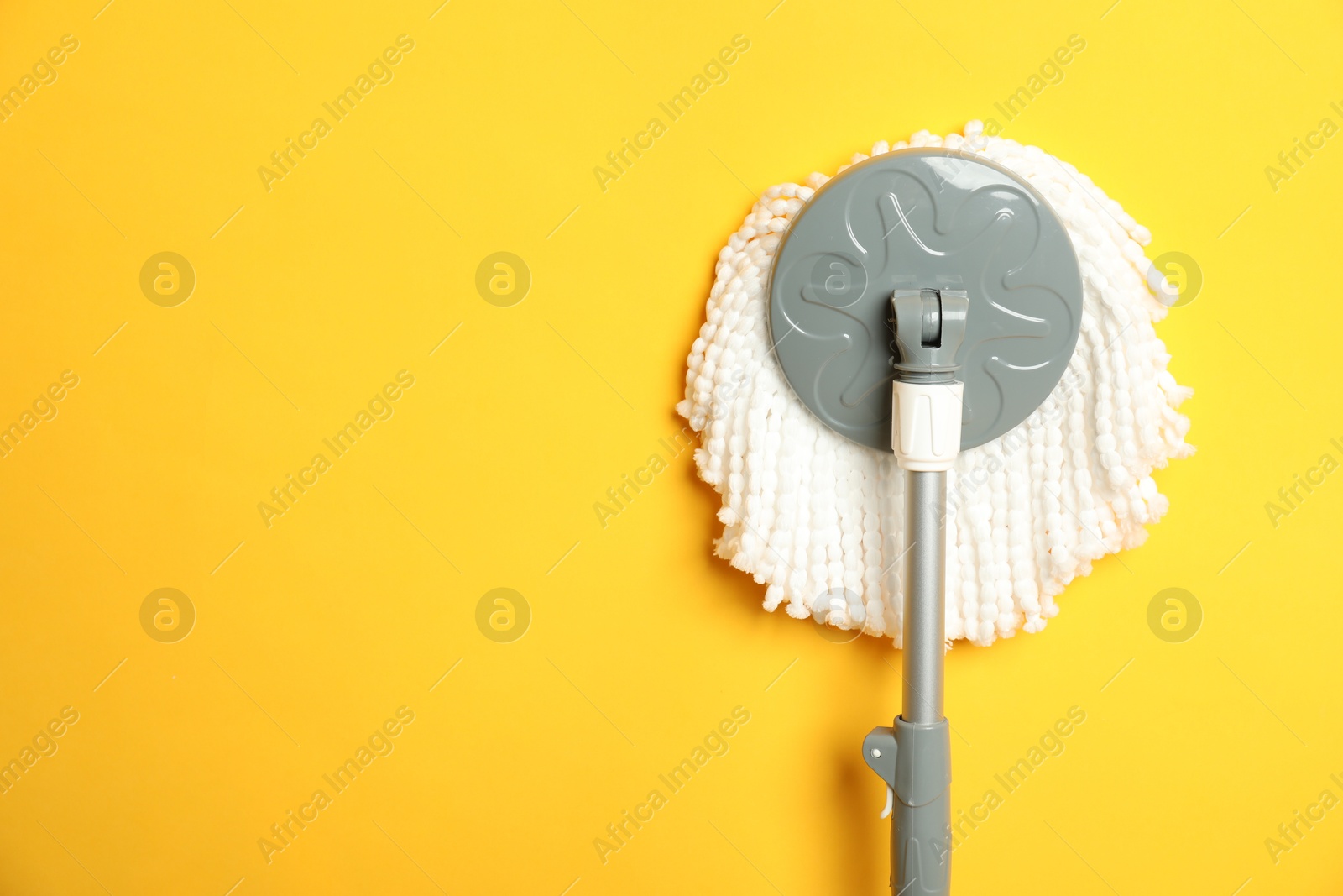 Photo of String mop on yellow background, top view. Space for text