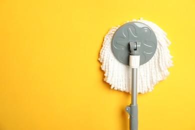 Photo of String mop on yellow background, top view. Space for text