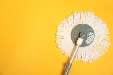 Photo of String mop on yellow background, top view. Space for text