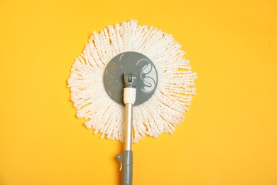 Photo of String mop on yellow background, top view