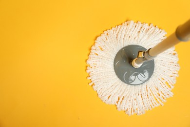 Photo of String mop on yellow background, top view. Space for text