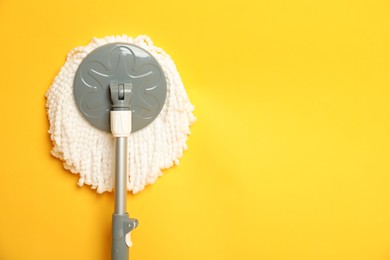 Photo of String mop on yellow background, top view. Space for text