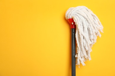 Photo of String mop on yellow background. Space for text