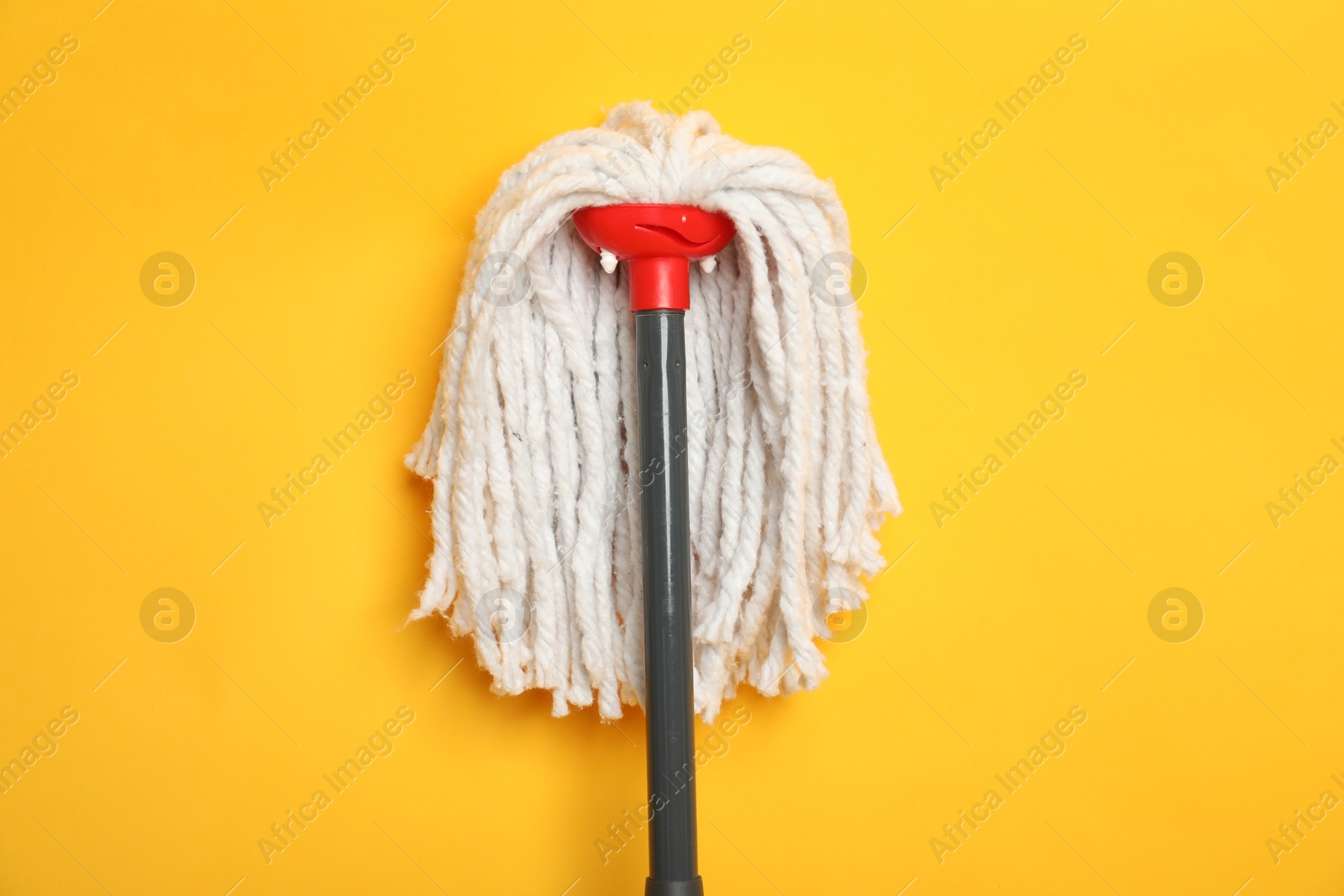 Photo of String mop on yellow background, top view