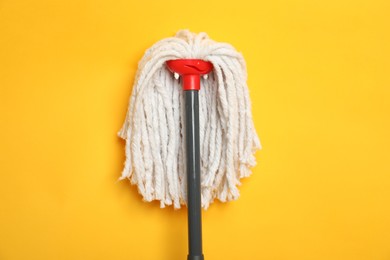 Photo of String mop on yellow background, top view